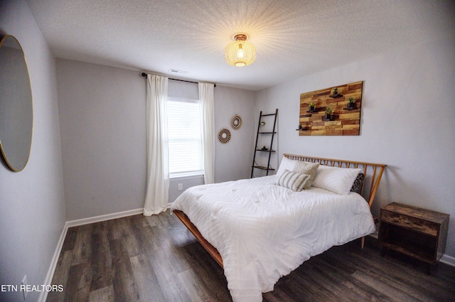 bedroom with wood finished floors, baseboards, and a textured ceiling