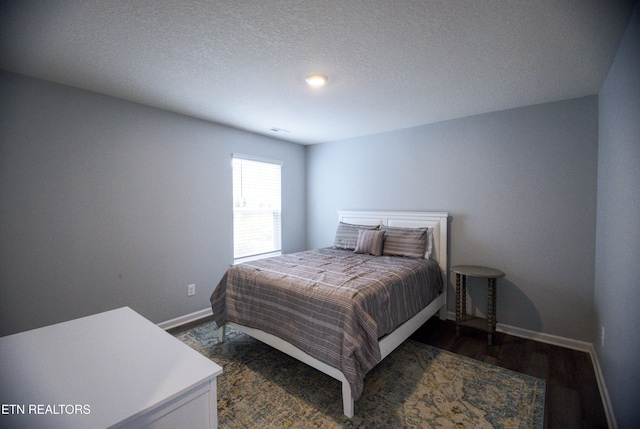 bedroom with baseboards, wood finished floors, and a textured ceiling
