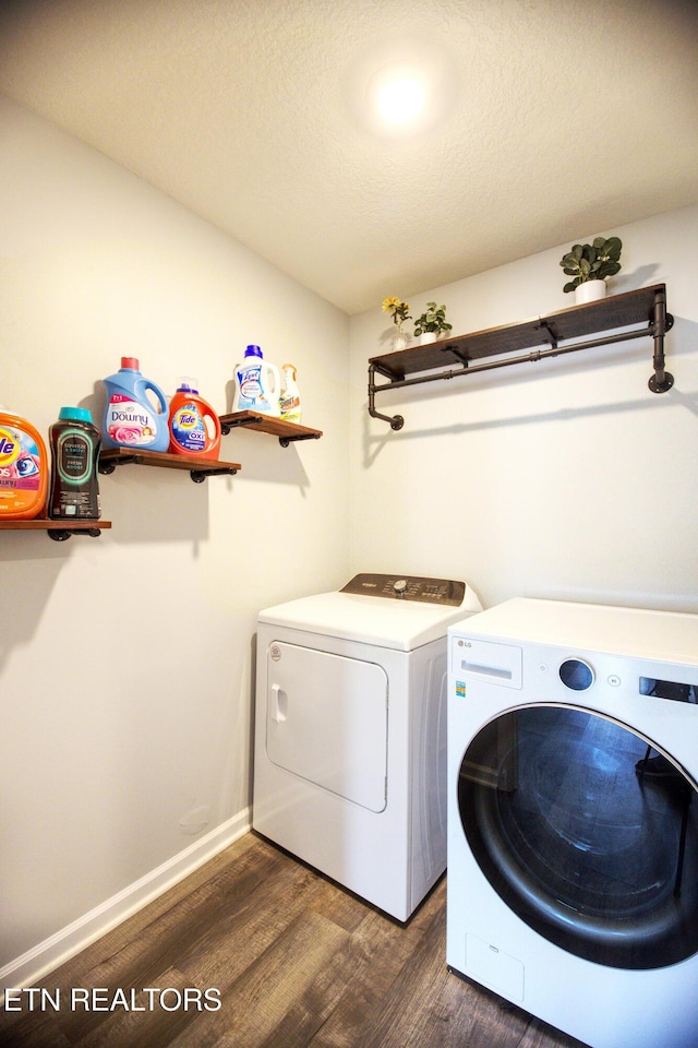 clothes washing area with washer and dryer, dark wood finished floors, and baseboards