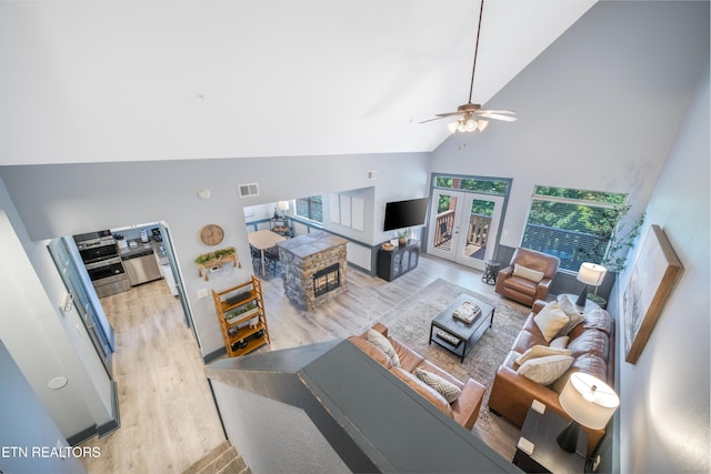 living room featuring high vaulted ceiling, light wood-style flooring, and a ceiling fan