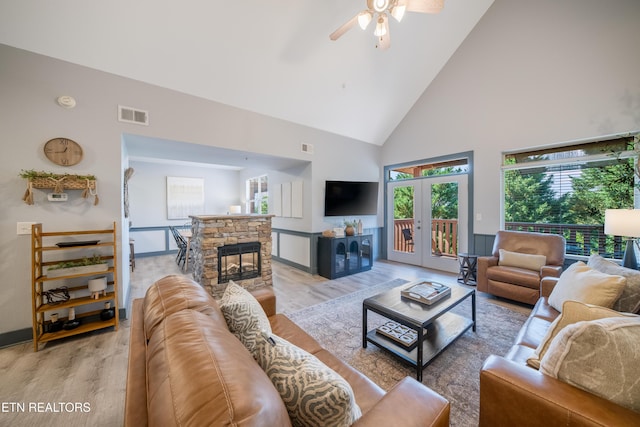 living area with light wood-style floors, high vaulted ceiling, ceiling fan, a fireplace, and baseboards