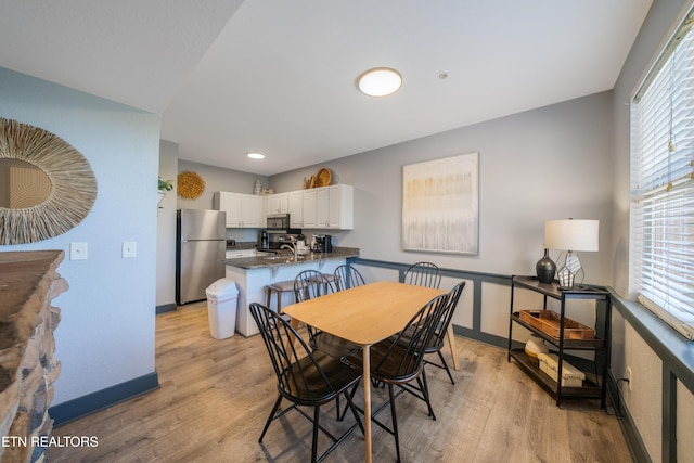 dining area featuring light wood-style flooring, baseboards, and plenty of natural light