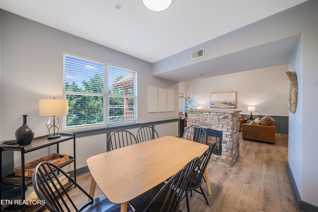 dining space featuring wood finished floors and a stone fireplace