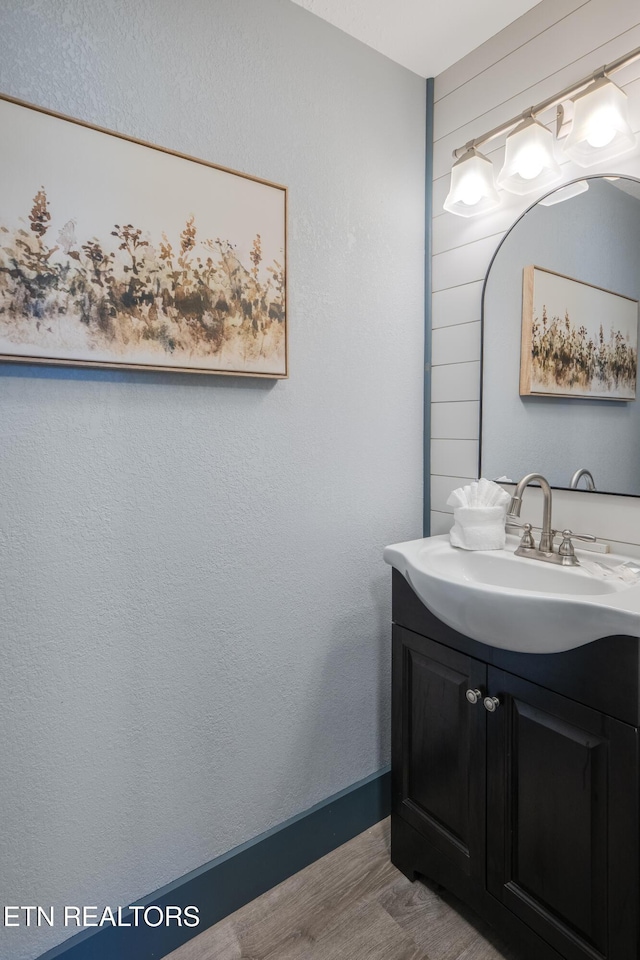 bathroom with wood finished floors, vanity, and baseboards