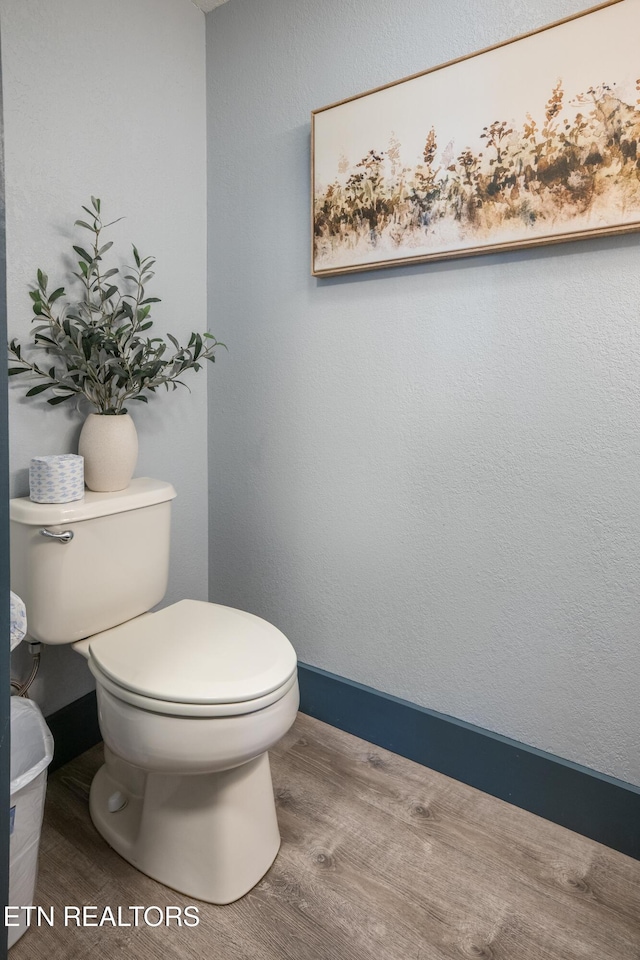 bathroom with toilet, wood finished floors, and baseboards