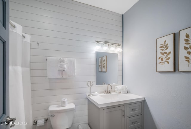 full bathroom with wooden walls, toilet, and vanity