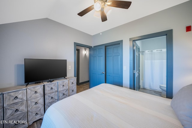 bedroom with wood finished floors, vaulted ceiling, a ceiling fan, a closet, and ensuite bath