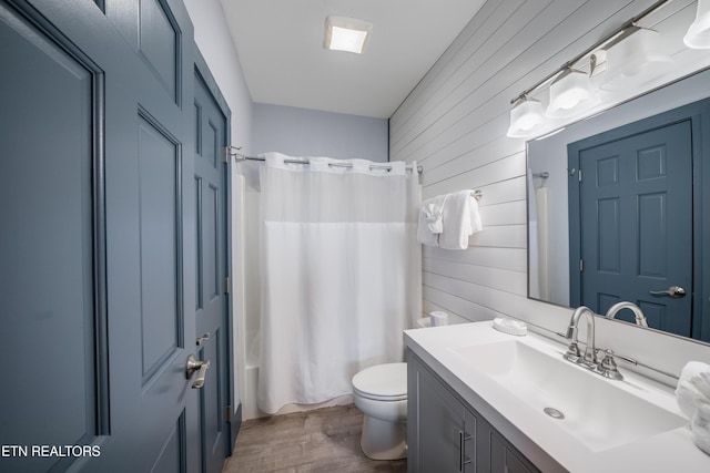 full bath with wooden walls, wood finished floors, toilet, vanity, and shower / bathtub combination with curtain
