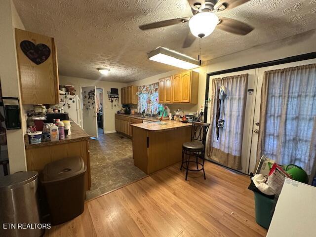 179 Granby Ln, Harrogate, TN 37752 - kitchen with a textured ceiling, a peninsula, a ceiling fan, a breakfast bar area, and freestanding refrigerator