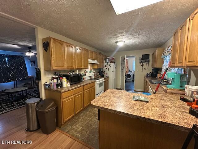 179 Granby Ln, Harrogate, TN 37752 - kitchen with white appliances, under cabinet range hood, a textured ceiling, washer / clothes dryer, and a peninsula