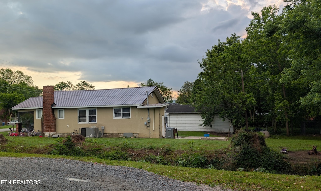 515 Winchester Ave, Middlesboro, KY 40965 - property exterior at dusk with cooling unit, metal roof, stucco siding, and a chimney