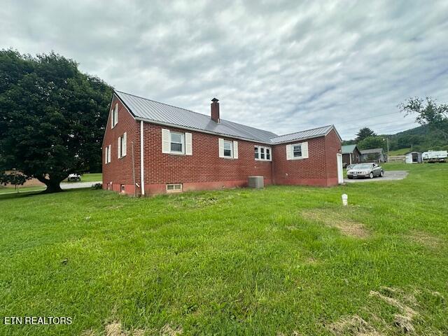 156 Beatty Rd, Rose Hill, VA 24281 - rear view of house featuring a chimney, central AC unit, brick siding, metal roof, and a lawn