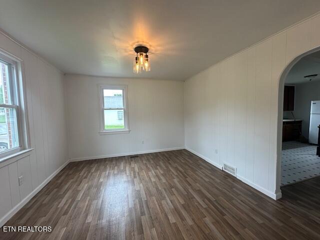 156 Beatty Rd, Rose Hill, VA 24281 - empty room featuring arched walkways, dark wood-style flooring, baseboards, and a decorative wall