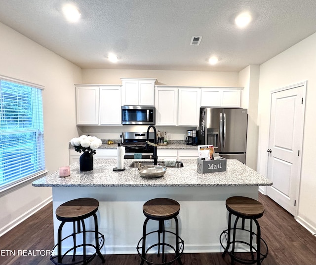 1013 Curly Top Ln, Knoxville, TN 37932 - kitchen with stainless steel appliances, an island with sink, a kitchen breakfast bar, dark wood-style floors, and a textured ceiling