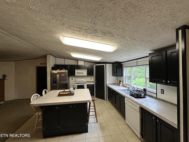 214 Hickory Grove Rd, Madisonville, TN 37354 - kitchen with white appliances, dark cabinetry, a breakfast bar, light countertops, and a kitchen island