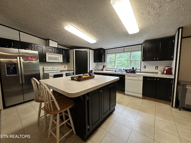 214 Hickory Grove Rd, Madisonville, TN 37354 - kitchen with white appliances, dark cabinets, light countertops, a kitchen island, and a textured ceiling
