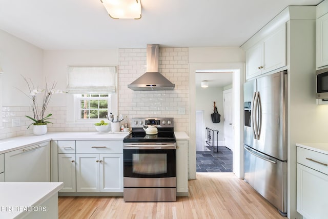 4051 Sutherland Ave, Knoxville, TN 37919 - kitchen featuring appliances with stainless steel finishes, wall chimney exhaust hood, backsplash, light wood finished floors, and light countertops
