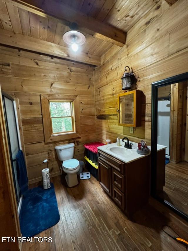 208 Charles Eaves Ln, Benton, TN 37307 - bathroom featuring wooden ceiling with exposed beams, hardwood / wood-style floors, wood walls, vanity, and toilet