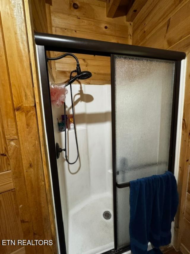 208 Charles Eaves Ln, Benton, TN 37307 - bathroom featuring a stall shower and wooden walls