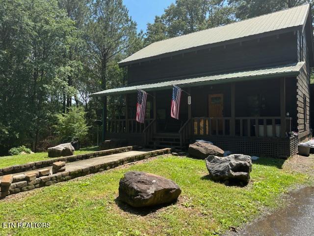 208 Charles Eaves Ln, Benton, TN 37307 - view of front of home with a porch, metal roof, a front lawn, and an outdoor fire pit