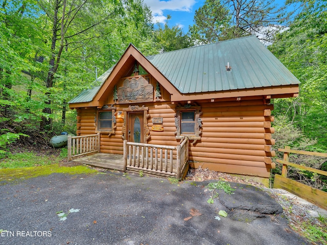 log-style house featuring log siding and metal roof