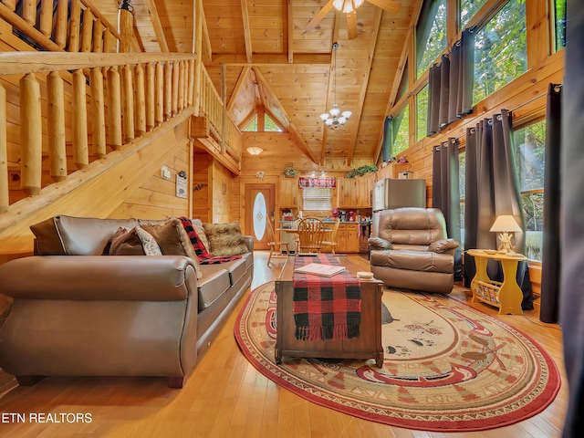 living room with wood ceiling with exposed beams, wood walls, high vaulted ceiling, light wood-style flooring, and ceiling fan