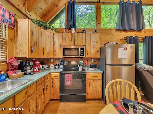 kitchen featuring appliances with stainless steel finishes, light wood-type flooring, vaulted ceiling, and light countertops