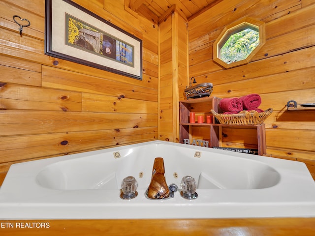 bathroom featuring wooden walls and a tub with jets