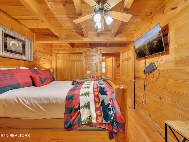 bedroom with wood walls, wood ceiling with exposed beams, and wood finished floors