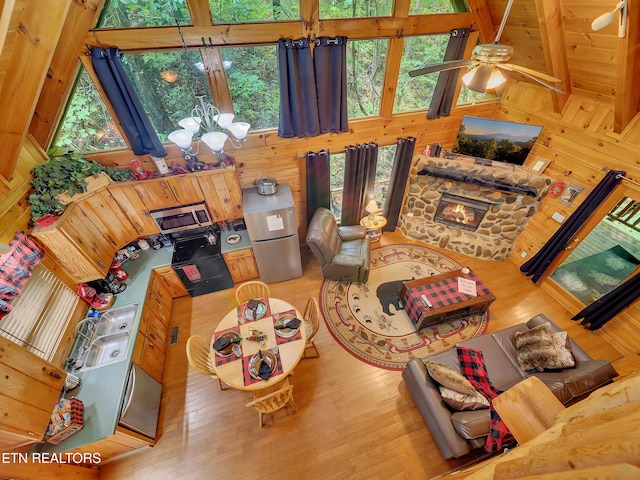 living area featuring hardwood / wood-style floors, a chandelier, wooden walls, and a ceiling fan