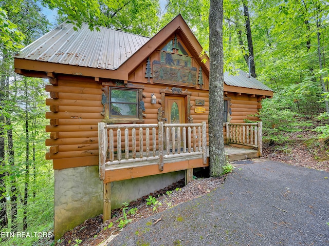 log cabin featuring log exterior, metal roof, and a wooden deck