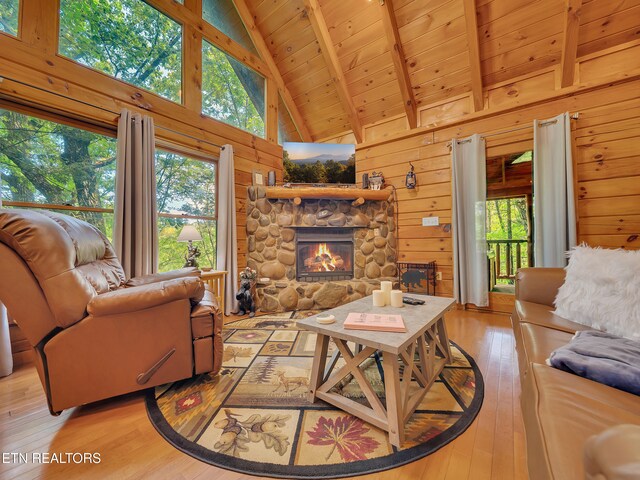 living area featuring light wood-style flooring, wooden ceiling with exposed beams, wood walls, a fireplace, and high vaulted ceiling