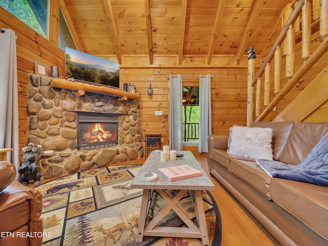 living area featuring wood ceiling, wood finished floors, a stone fireplace, and wood walls