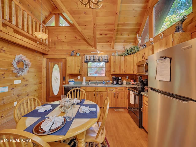 kitchen featuring stainless steel appliances, a sink, wood walls, light wood-style floors, and wooden ceiling with exposed beams