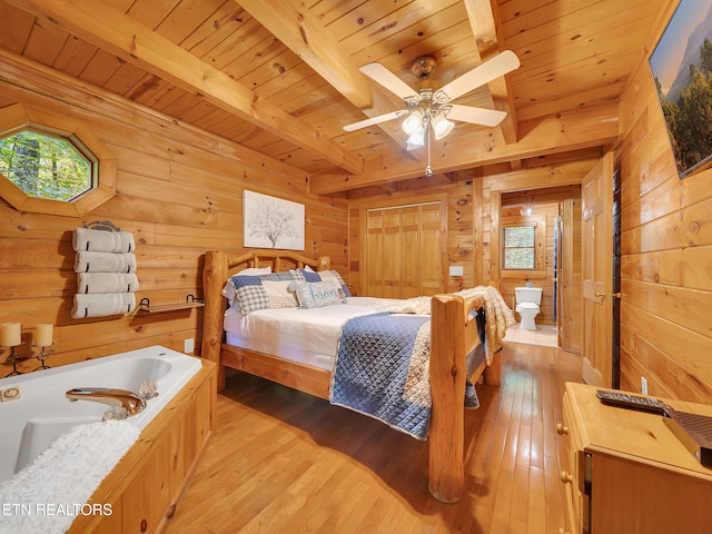 bedroom featuring wood walls, wooden ceiling with exposed beams, and light wood-style floors