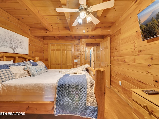bedroom with wood walls, wooden ceiling with exposed beams, and wood-type flooring
