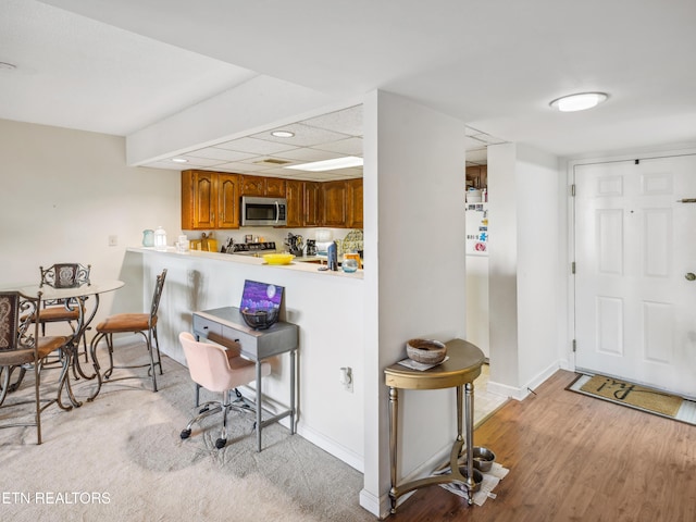 203 Regal Tower, Maryville, TN 37804 - kitchen with stainless steel microwave, brown cabinetry, baseboards, light countertops, and light wood-type flooring