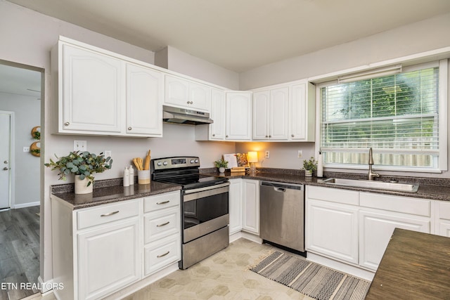 6944 Berry Ln, Knoxville, TN 37914 - kitchen featuring appliances with stainless steel finishes, a sink, under cabinet range hood, white cabinets, and dark stone countertops