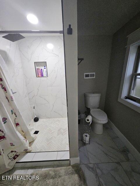 828 Noragate Rd, Knoxville, TN 37919 - full bath with marble look tile flooring, a stall shower, and toilet