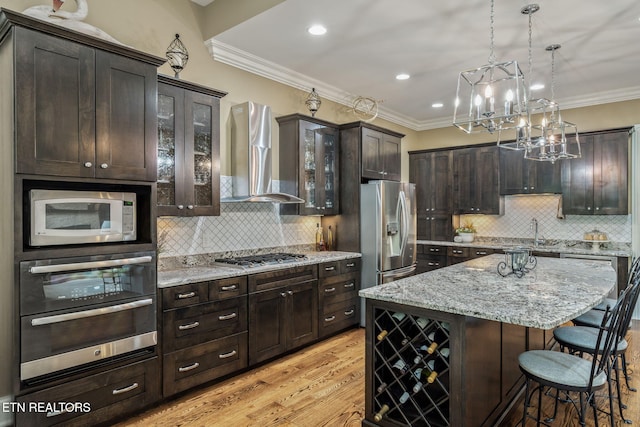 111 Winchester Cir, Oak Ridge, TN 37830 - kitchen with appliances with stainless steel finishes, wall chimney range hood, a sink, a kitchen bar, and light wood-type flooring