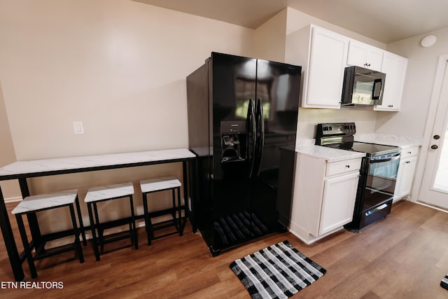 1799 Baker Hwy, Huntsville, TN 37756 - kitchen featuring black appliances, light wood-style floors, white cabinets, and light stone counters
