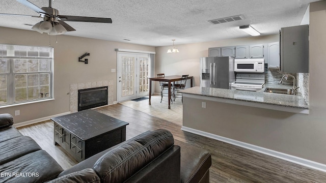1316 Mountain Meadows Way, Sevierville, TN 37862 - living area with baseboards, a ceiling fan, light wood-type flooring, a tiled fireplace, and a textured ceiling