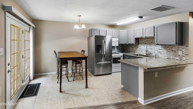 1316 Mountain Meadows Way, Sevierville, TN 37862 - kitchen with white appliances, gray cabinets, a peninsula, decorative backsplash, and a textured ceiling