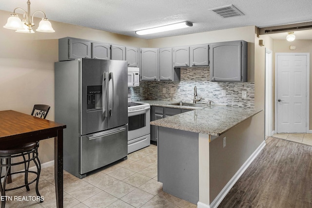 1316 Mountain Meadows Way, Sevierville, TN 37862 - kitchen featuring white appliances, gray cabinets, a sink, a peninsula, and backsplash