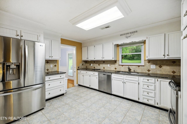 7613 Luscombe Dr, Knoxville, TN 37919 - kitchen featuring stainless steel appliances, a sink, ornamental molding, tasteful backsplash, and white cabinetry