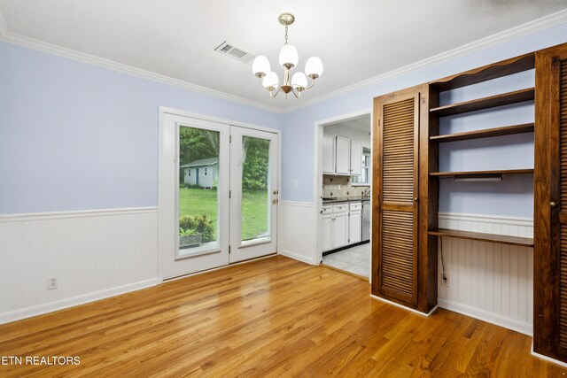 7613 Luscombe Dr, Knoxville, TN 37919 - unfurnished dining area featuring a chandelier, light wood-style floors, a wainscoted wall, and ornamental molding