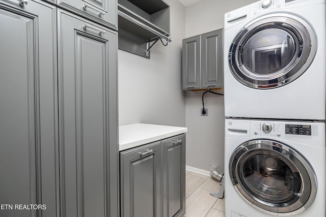 1025 Ree Way Unit 20, Knoxville, TN 37909 - laundry area featuring cabinet space, stacked washer / dryer, and baseboards