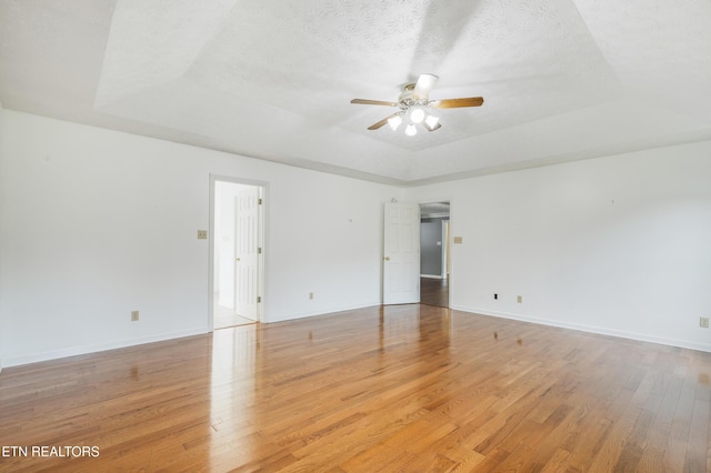 6799 Hickory Creek Rd, Lenoir City, TN 37771 - empty room featuring a tray ceiling, a ceiling fan, light wood-style flooring, baseboards, and a textured ceiling