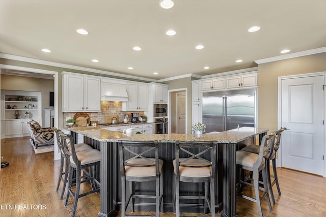 436 Silent River Ln, Loudon, TN 37774 - kitchen featuring built in appliances, ornamental molding, light stone counters, white cabinetry, and a kitchen bar