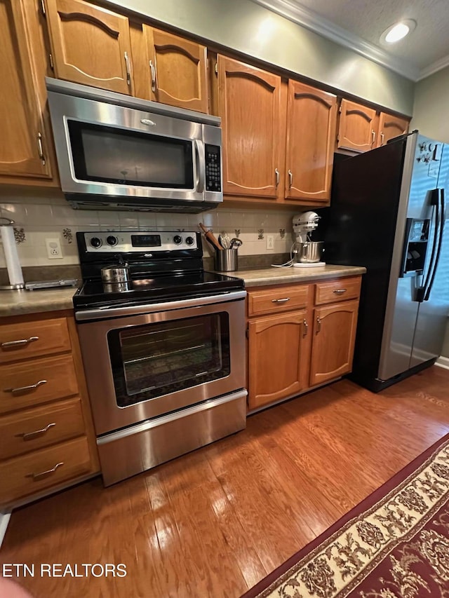 5230 Brig Ln, Knoxville, TN 37914 - kitchen with stainless steel appliances, ornamental molding, dark wood finished floors, tasteful backsplash, and brown cabinetry